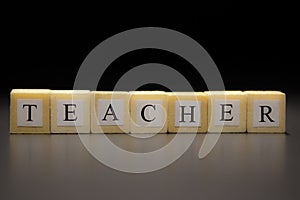 The word TEACHER written on wooden cubes isolated on a black background