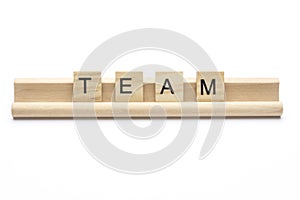 Word ``team`` on scrabble wooden letters on a rack, isolated on