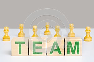 The word team on wooden cubes among chess pieces pawns