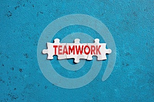 The word teamwork written on puzzle pieces on blue background