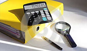 Word tenders on calculator on office desk with stationery, top view