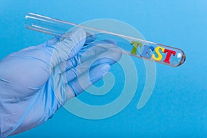 Word test in test-tube holding a gloved hand