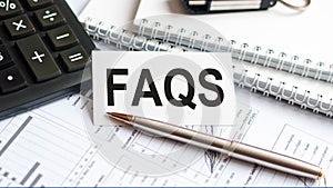 Word text FAQS on white paper card, business concept