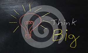 Word think big and light bulb drawn with colorful chalk on a blackboard, business concept