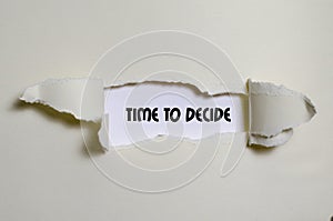 The word time to decide appearing behind torn paper