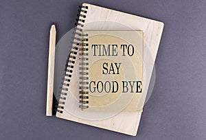 Word TIME TO SAY GOOD BYE on notebook with pencil on the grey background