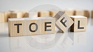 word TOEFL on wooden cubes, gray background