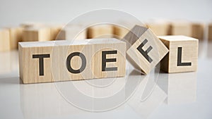 word TOEFL on wooden cubes, gray background.