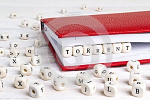 Word Torrent written in wooden blocks in red notebook on white w