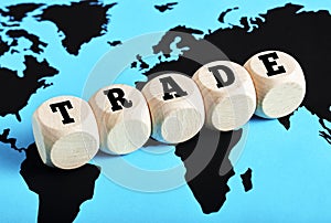 The word trade written on wooden cubes on world map background. International business trade or logistic transportation