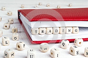 Word Trading written in wooden blocks in red notebook on white w