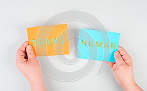 The word transhuman is standing on two pieces of paper, holding the message in the hands, future technology, post human, science photo