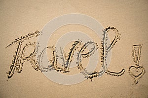 The word travel written in the sand