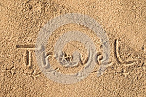 Word Travel written in the sand on the beach.  Summer travel concept. Birds footprints on yellow sand