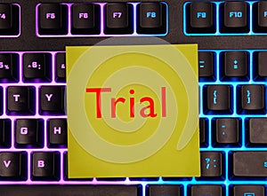 Word trial on yellow paper on a backlit keyboard background.