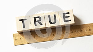 Word true made from wooden blocks on white background