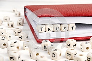 Word Trust written in wooden blocks in red notebook on white woo