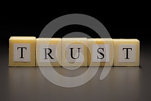 The word TRUST written on wooden cubes isolated on a black background