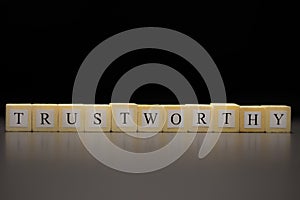 The word TRUSTWORTHY written on wooden cubes, isolated on a black background photo