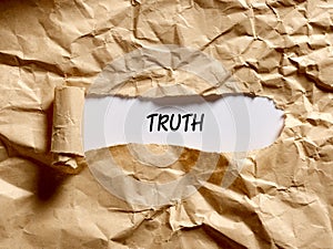 The word truth written under a brown torn paper