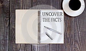 Word Uncover the Facts with pen and cofee. business concept