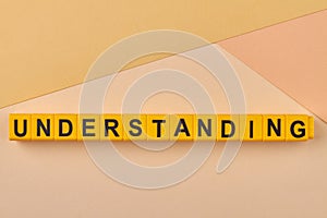 The word UNDERSTANDING written on yellow cubes against light background.