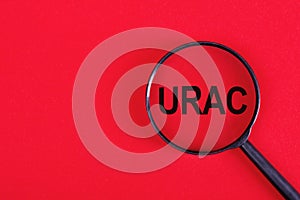 The word URAC on magnifying glass, redbackground, business concept photo