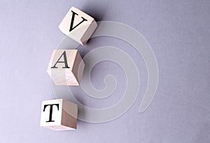 Word VAT on wooden block on the grey background