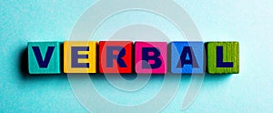 The word VERBAL is written on multicolored bright wooden cubes on a light blue background photo