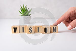 The word Vision on a wooden toy blocks with womans hand