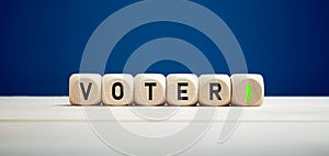 The word voter with upward arrow on wooden cubes. Elections and increasing voter turnout
