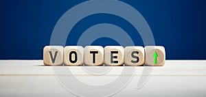 The word votes with upward arrow on wooden cubes. Elections and votes concept photo