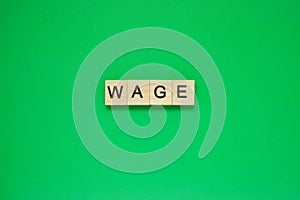 Word wage. Top view of wooden blocks with letters on green surface