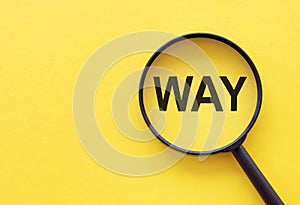 The word WAY is written on a magnifying glass on a yellow background. the concept of finding the right way