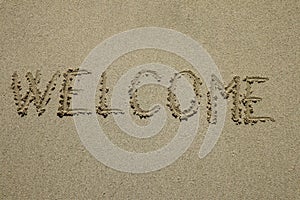 Word welcome written on the sand as the background