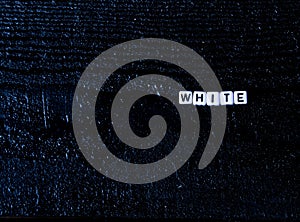 The word `white` made of cubes on a black wooden background. black background,