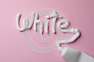 Word White written with toothpaste and tube on pink background, top view