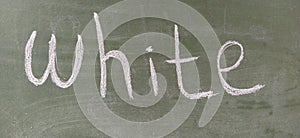 The word white written in white chalk on a green chalkboard