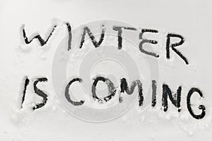 Word winter is coming scraped by hand on the frozen rear glass of car, auto glass covered with snow, cold winter season concept,