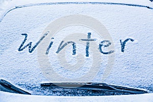 Word winter on the frozen glass of a car windshield. Car winter season concept