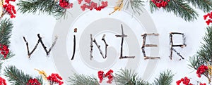The word winter written with broken wooden sticks on snow background