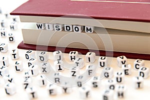 Word wisdom written with letters between a book pages white background with letters spread around education reading concept