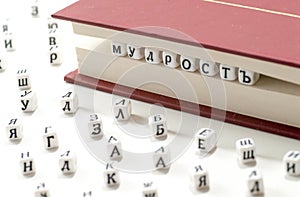 Word wisdom written win cyrillic letters between book sheets and cyrillic letters scatter on white background concept abstract