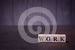 The word work on wooden cubes, on a dark background, light wooden cubes signs, symbols signs
