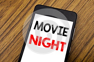 Word, writing handwriting Movie Night. Business concept for Wathing Movies Written on mobile phone cellphone, wooden background w