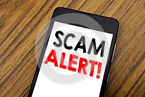 Word, writing handwriting Scam Alert. Business concept for Fraud Warning Written on mobile phone cellphone, wooden background with