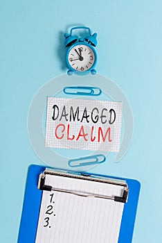 Word writing text Damages Claim. Business concept for Demand upon the insurer for compensation for a damage Alarm clock clipboard