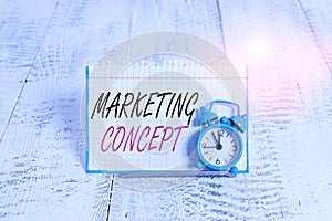 Word writing text Marketing Concept. Business concept for the strategy that firms adopt to satisfy customers Mini blue alarm clock