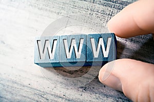 The Word WWW On Wooden Blocks And Arranged By Male Fingers On A Table