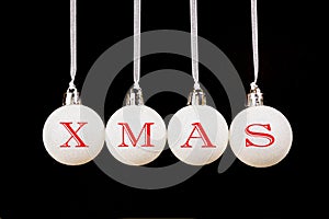 Word xmas on white christmas balls hanging on black background